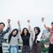 five young people hanging out and raise hand together on the building rooftop